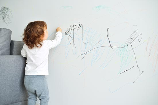 Kids Drawing on the wall with crayon